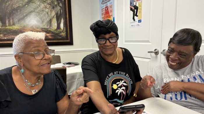 group of older adults looking at a phone and smiling